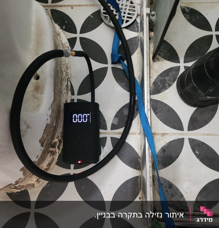מד לחץ דיגיטלי מחובר לצינור ליד ניקוז